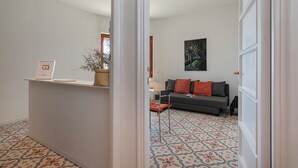 A modern living room with a grey sofa, red cushions, a small table, and a potted plant. - A Few Steps from the Sea by Wonderful Italy (Recco)