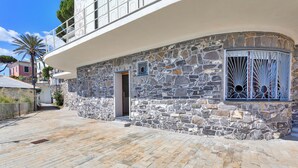 A stone building with a balcony, a door, and a window with decorative bars. - A Few Steps from the Sea by Wonderful Italy (Recco)