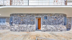 A stone building with a wooden door, a balcony, and a metal railing. - A Few Steps from the Sea by Wonderful Italy (Recco)