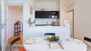 A dining area with a white table set for four, a black cabinet above the counter, and a small potted plant on the counter. - A Few Steps from the Sea by Wonderful Italy (Recco)