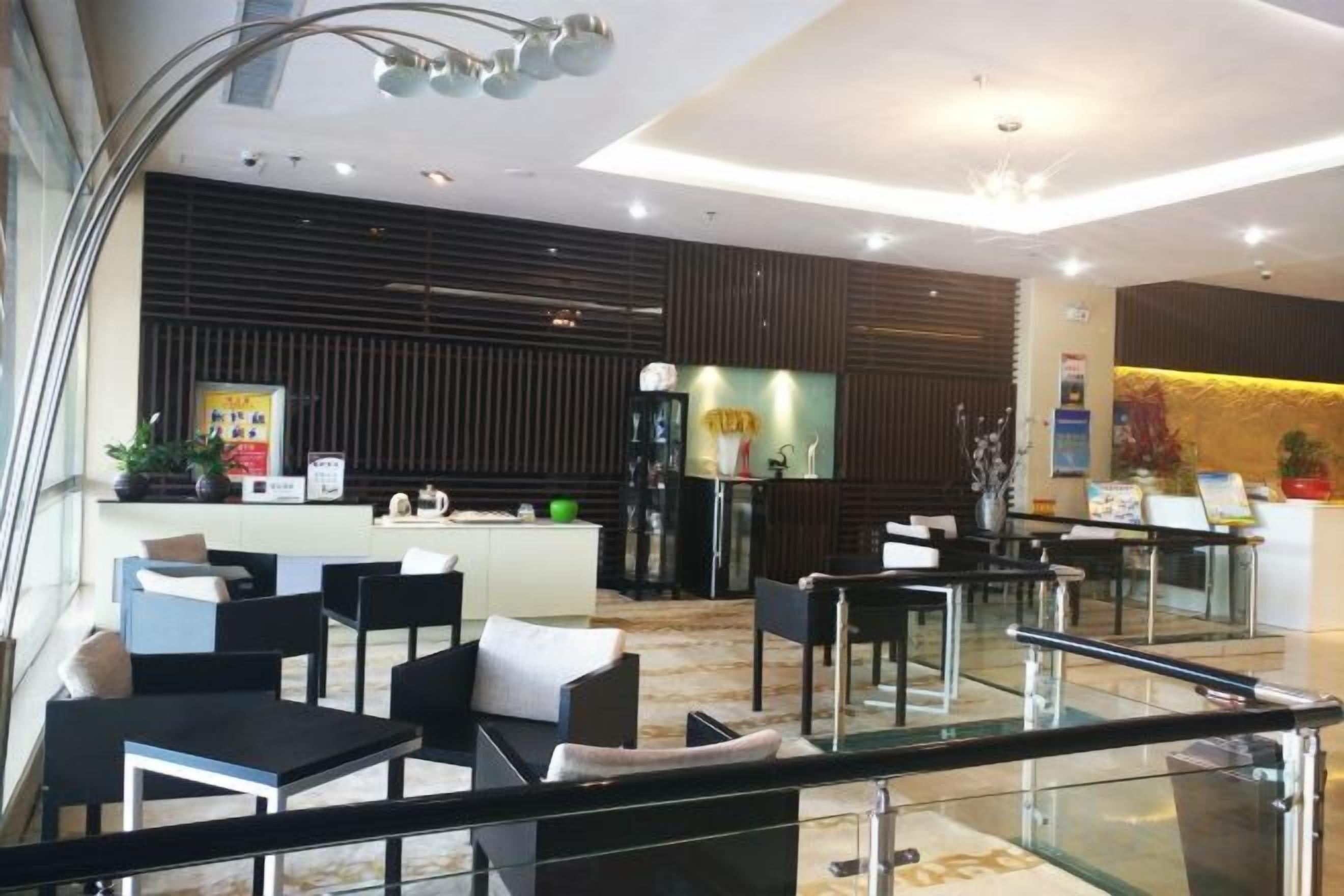 A hotel lobby with a reception desk, seating area, and a staircase.