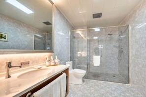 A bathroom with a glass-enclosed shower, a sink with a mirror, and a toilet. - Huili Business Apartment (Jiayuguan Donghu Scenic Area Datang Food Street Branch) (Jiayuguan)