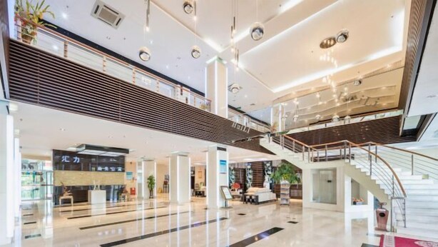 Eine großzügige, moderne Lobby mit einer zentralen Treppe, hohen Decken und einem glatten, polierten Boden.