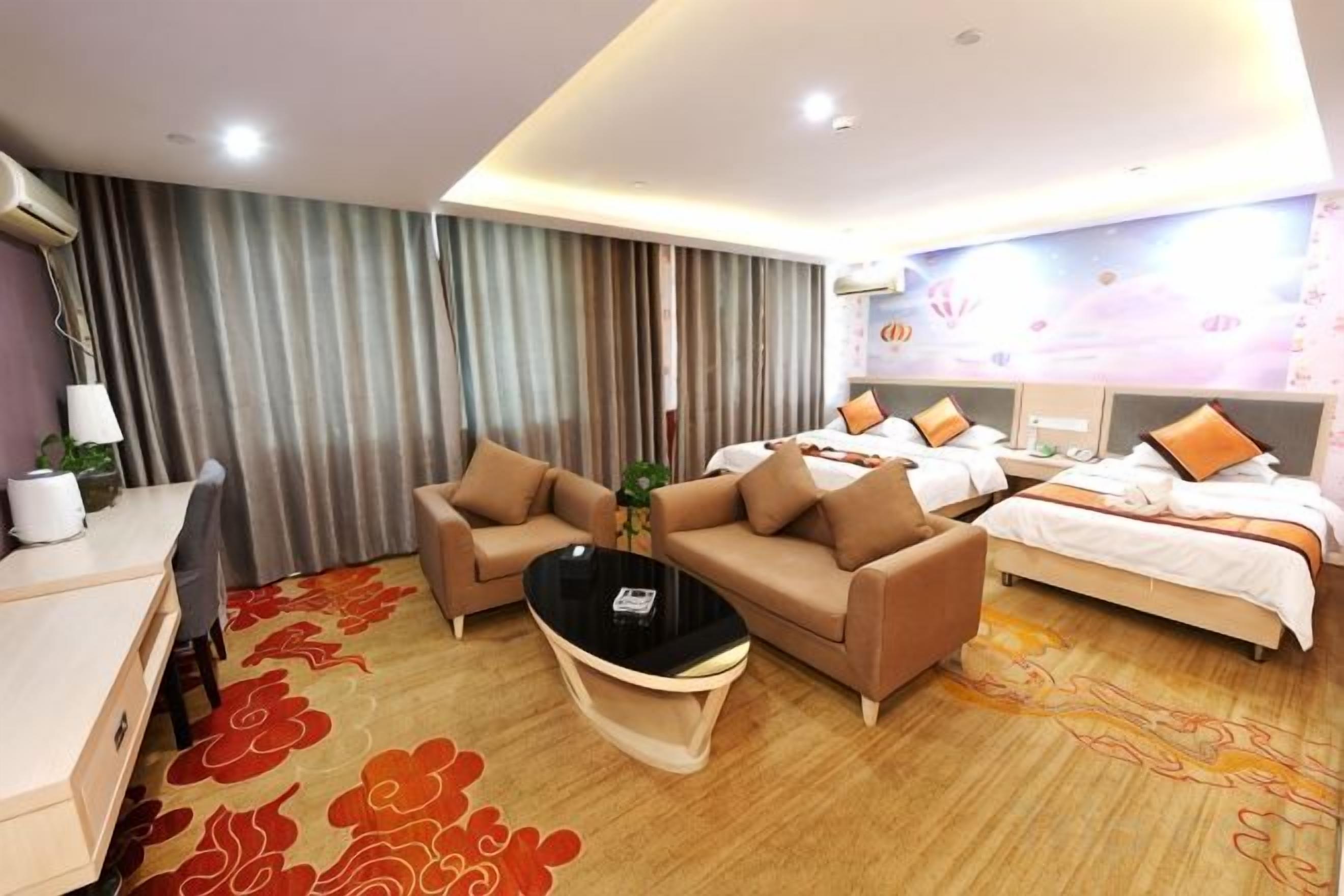 A hotel room with a bed, two sofas, a coffee table, and a desk.