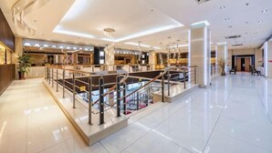 Eine geräumige Lobby mit einer zentralen Treppe, einer Rezeption und einem modernen Design.