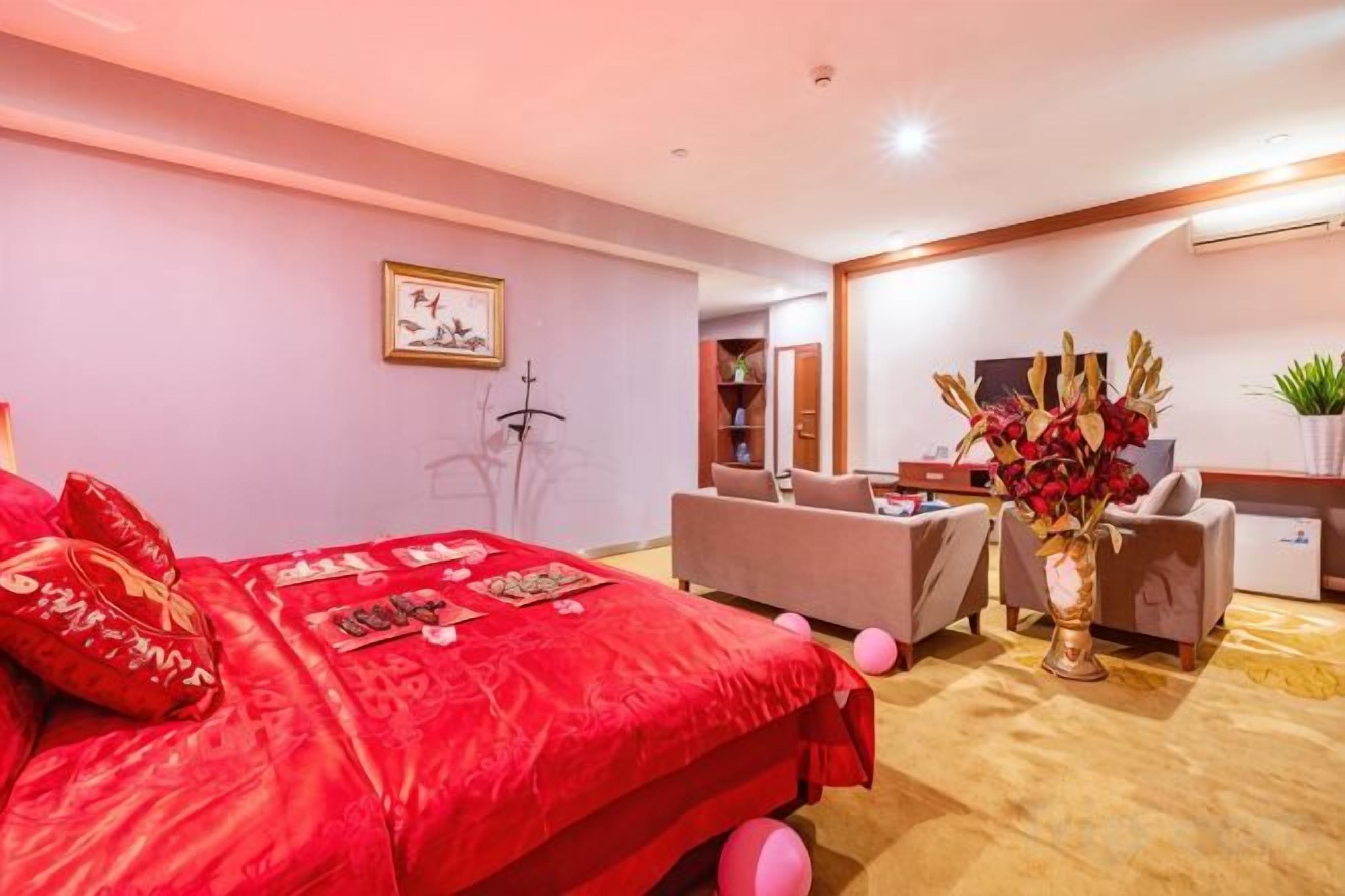 Una habitación de hotel con una cama grande, un escritorio, una silla y un florero con flores.