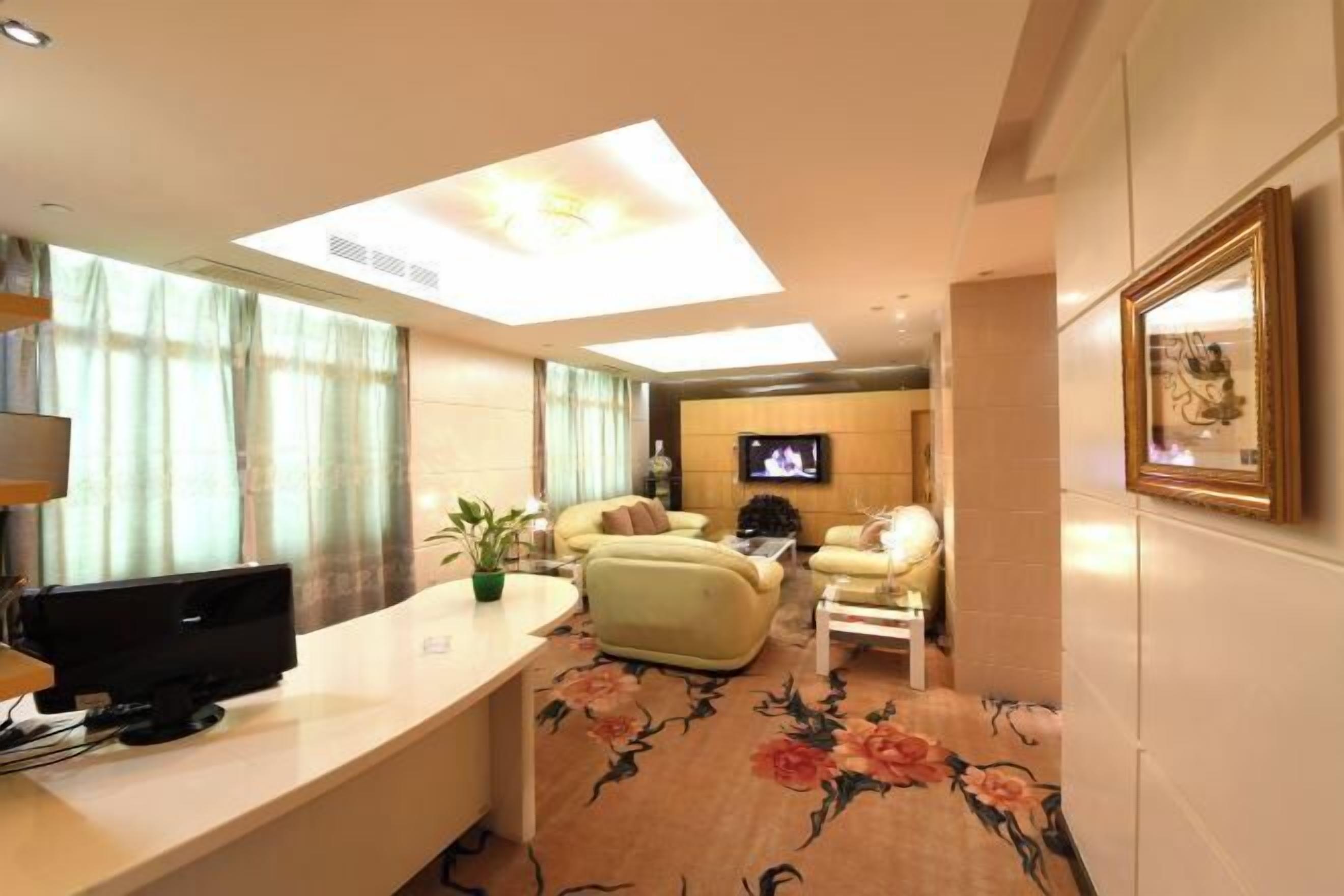 Een hotelkamer met een wandgemonteerde flatscreen-tv, een bureau met een computer, twee sofa's en een dakraam.