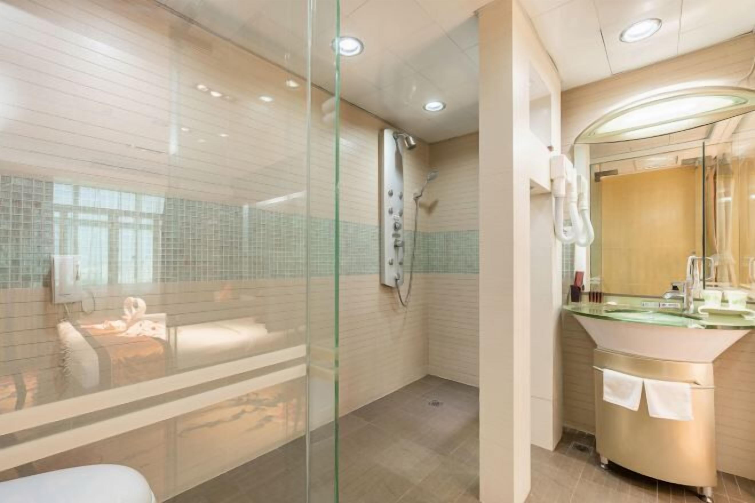 A modern bathroom with a glass shower enclosure, a glass-topped vanity, and a visible towel rack.