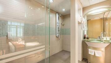A modern bathroom with a glass shower enclosure, a glass-topped vanity, and a visible towel rack.
