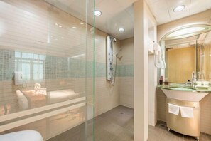 Un baño moderno con cabina de ducha de vidrio, tocador con tapa de cristal y un perchero visible.