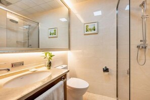 Un baño moderno con un espejo grande, un lavabo, un inodoro y una ducha con cerramiento de vidrio.