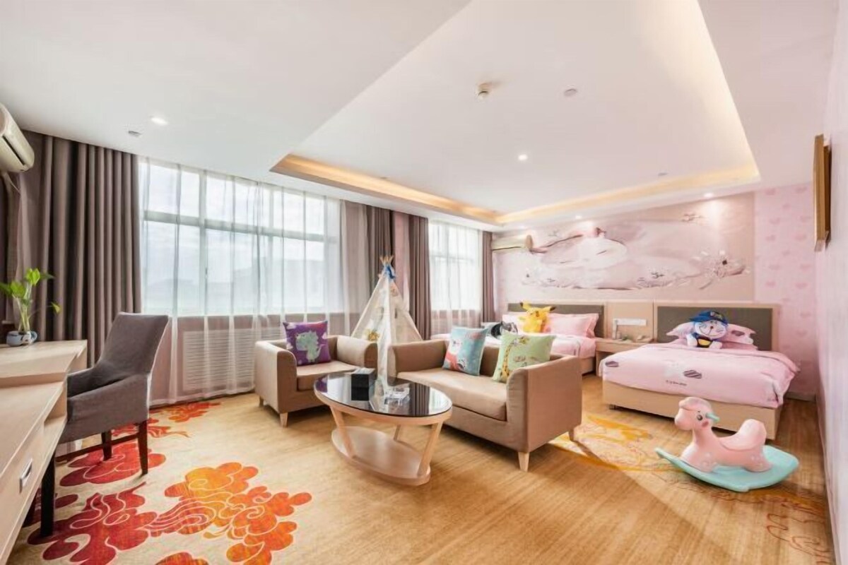 Una habitación de hotel moderna con sofá, una mesa de comedor, cama y un ventanal grande.