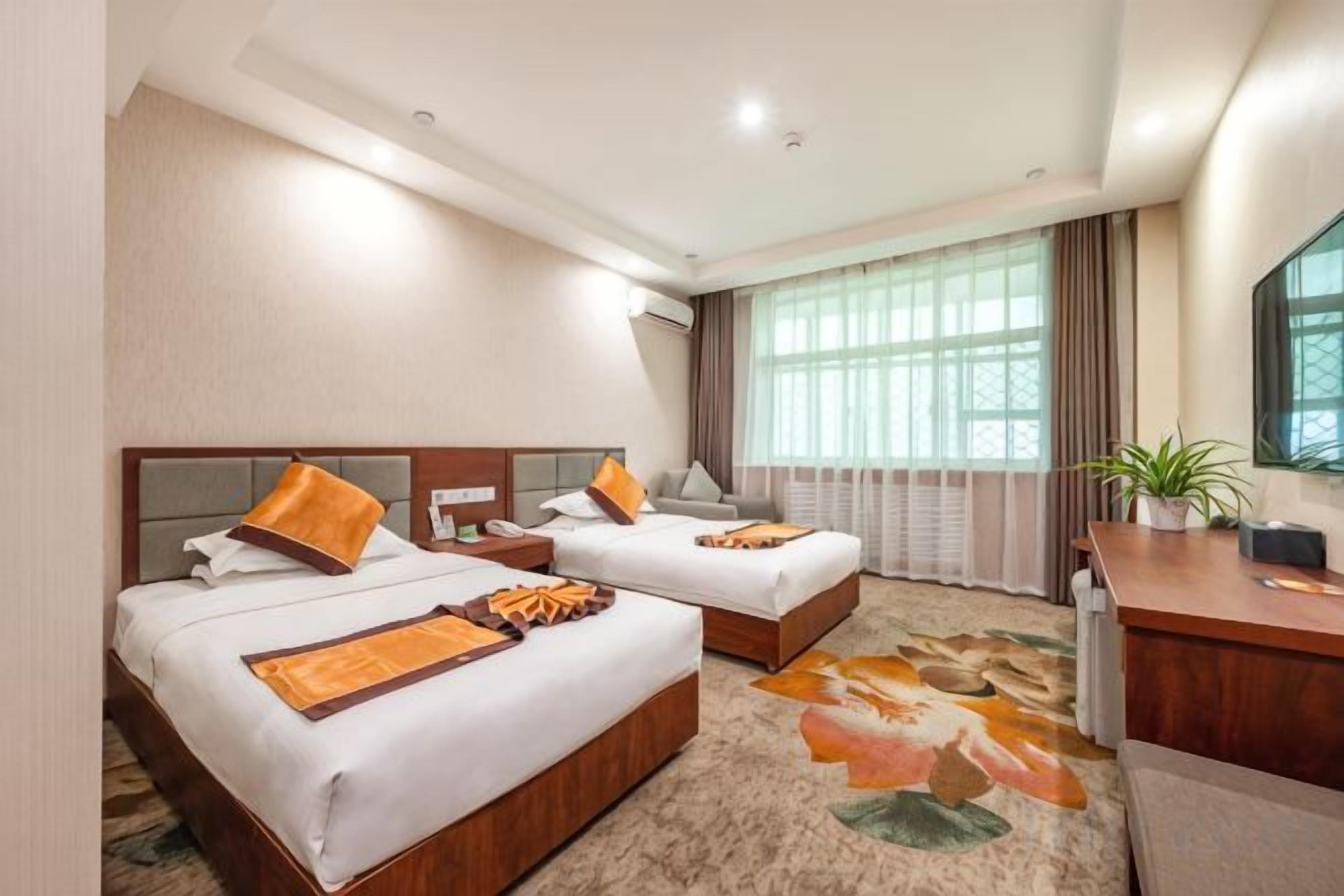 A hotel room with two beds, a desk, a chair, and a large window with curtains.