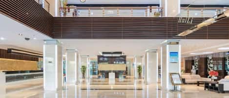 Eine geräumige Lobby mit einer Rezeption, einer Treppe und einer Sitzecke.