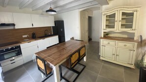Una cocina moderna con armarios blancos, una mesa de comedor de madera y un refrigerador negro.