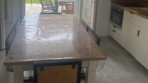 Una cocina moderna con una mesa de madera, armarios blancos y vista al patio trasero.