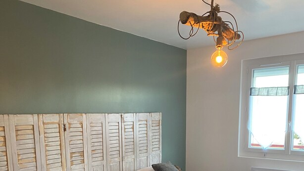 Una habitación con dos camas de madera, cabeceras de madera, una lámpara y una ventana con persianas.
