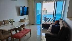 Un salon moderne comprenant une table à manger, un canapé et un téléviseur fixé au mur.