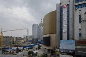 Une vue urbaine mettant en évidence un bâtiment imposant, doté d’un grand écran numérique et d’une enseigne avec des caractères chinois.