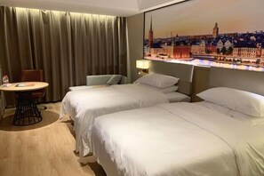 Una habitación de hotel con dos camas, una mesa, una silla, una lámpara y un cuadro de un paisaje urbano en la pared.