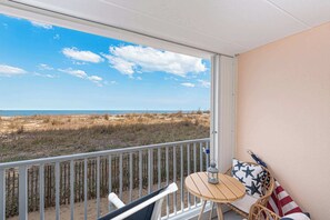 Un balcone con vista sulla spiaggia, una sedia in vimini, un tavolino e una bandiera americana.