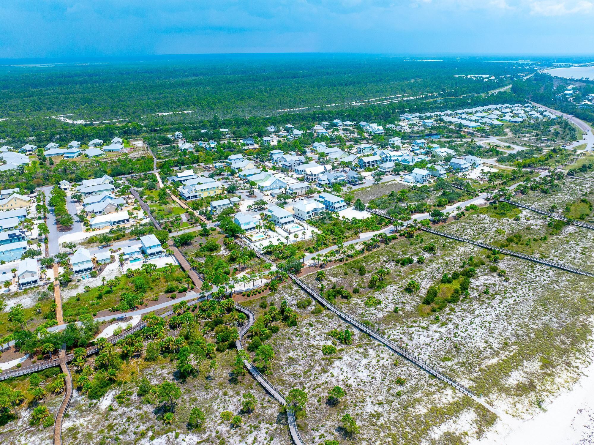 An aerial view of a coastal residential area with houses, roads, and a beach.