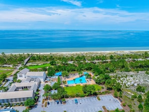 A resort with a swimming pool, parking lot, and a view of the ocean. - Pixie's Paradise (Port St. Joe)