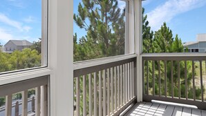 A balcony with a view of trees and a building in the background. - Pixie's Paradise (Port St. Joe)