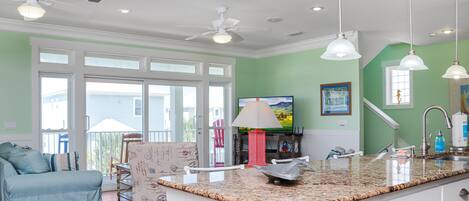 A modern kitchen with a granite countertop, white cabinetry, and a ceiling fan.