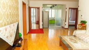 Una sala de estar moderna con piso de madera, un sofá, un televisor y un tapete rojo.