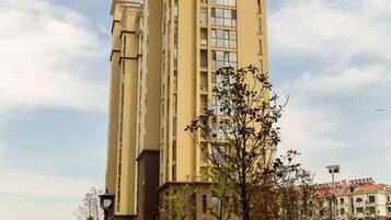 A high-rise building with multiple floors, a clear sky, and some trees in the foreground.