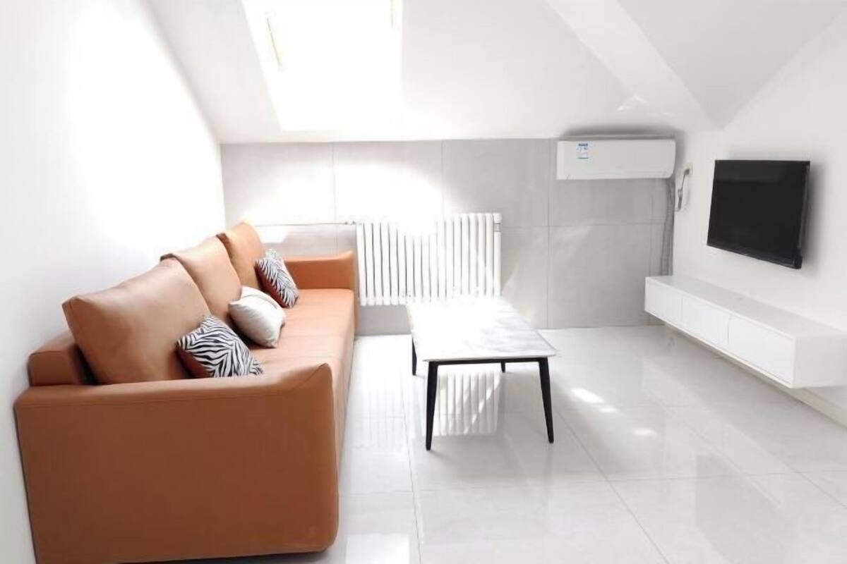 A modern living room with a sofa, a coffee table, a TV, and a radiator.