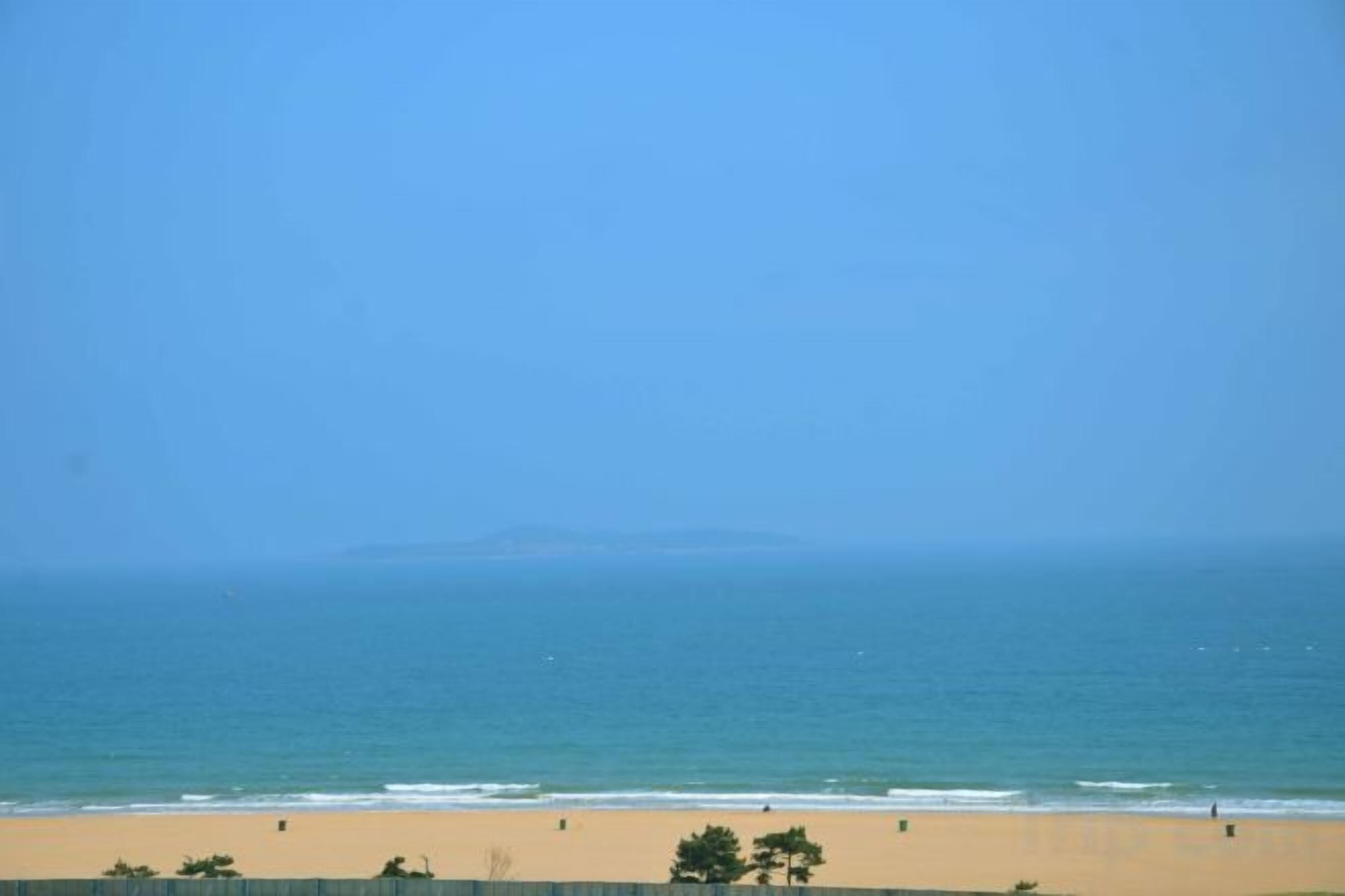 A beach with a clear view of the ocean and distant land.
