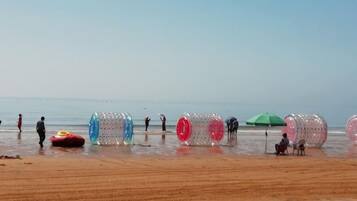 A beach with people, colorful inflatable tubes, and a green umbrella.