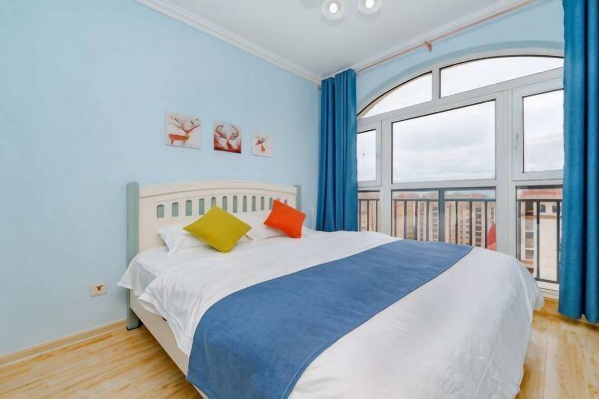 A bedroom with a bed, a window, and a balcony.
