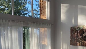 Un dormitori amb un finestral gran, un llit i un quadre a la paret.