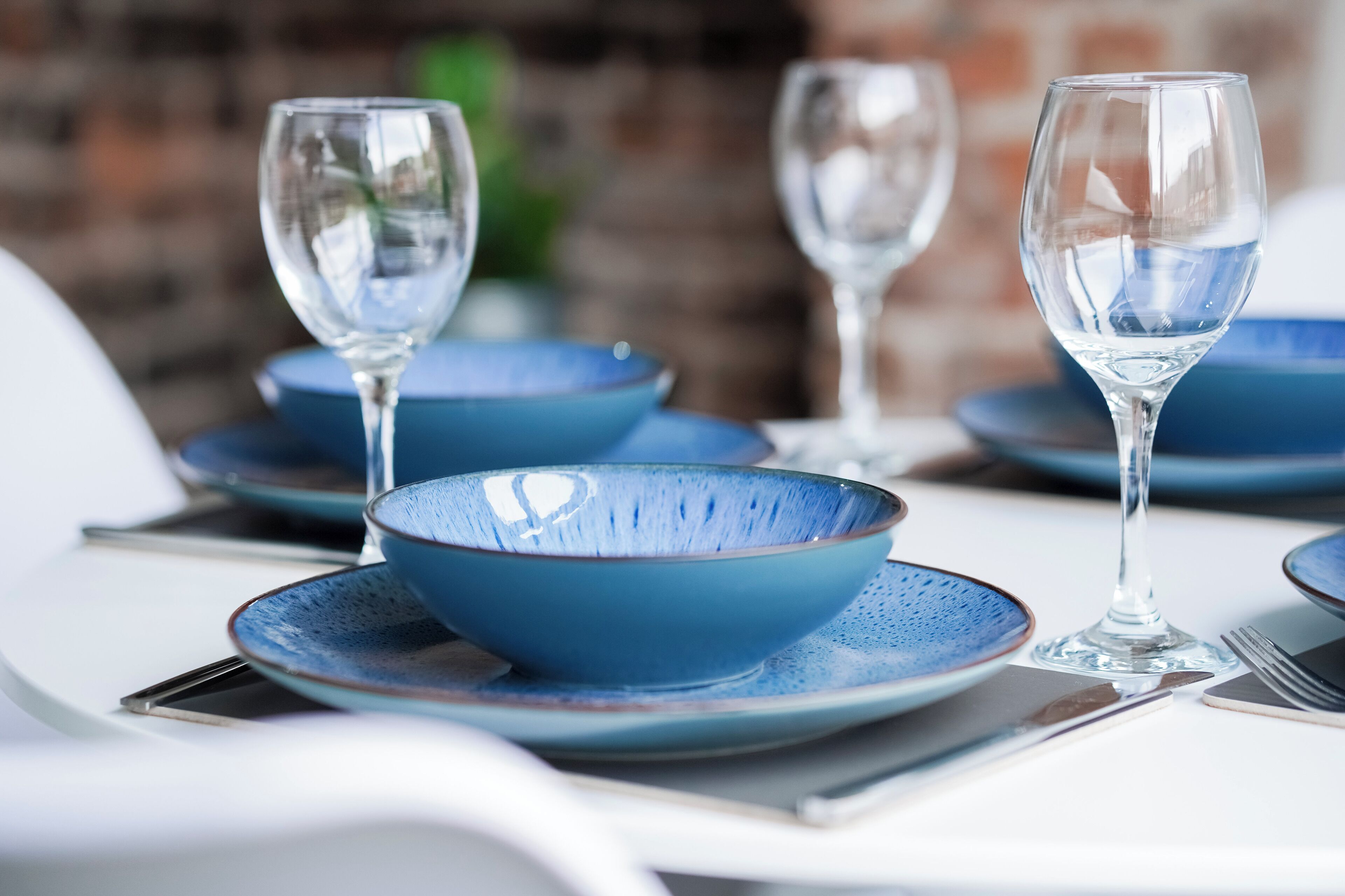 A table set with blue bowls and wine glasses, suggesting a formal dining arrangement.