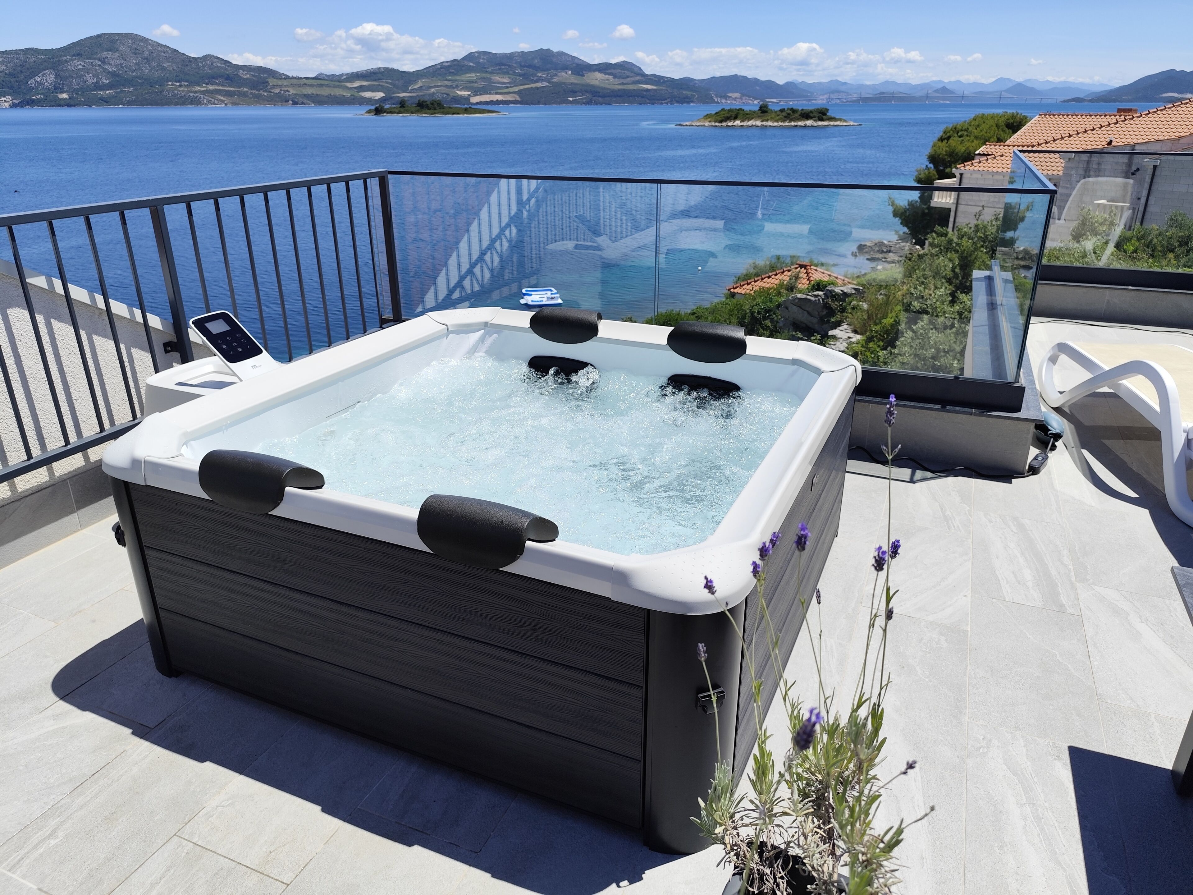 Un jacuzzi sur un balcon avec vue sur la mer et les montagnes.