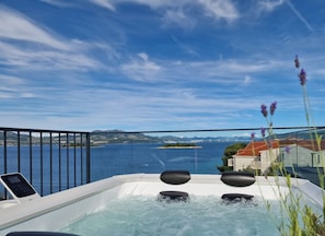 Uma banheira de hidromassagem com vista para um corpo d'água e uma ponte ao longe.