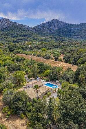 A property with a swimming pool, surrounded by dense vegetation and mountains in the background.