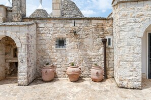 A stone building with a courtyard, featuring three terracotta pots and a small window.