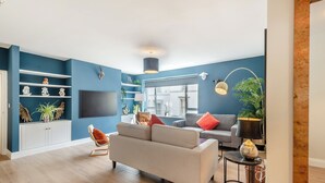 A modern living room with a grey sofa, a television, and decorative shelves. - Station Street Apartment (Cockermouth)