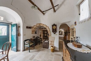 A rustic interior with stone walls, wooden furniture, and a vintage clock.
