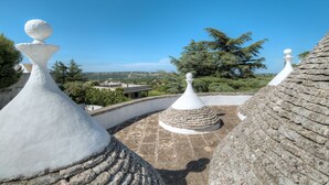 A rooftop terrace with stone structures and a clear view of the surrounding landscape. - Trullo Corbezzolo by Rentbeat (Locorotondo)