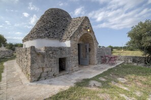 Un bâtiment en pierre surmonté d’un dôme, doté d’une entrée et d’un petit espace extérieur aménagé pour s’asseoir.