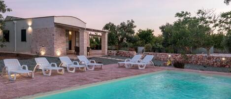A poolside area with lounge chairs and a pool.