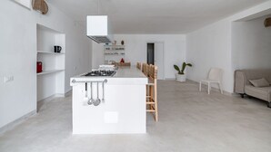 Een moderne keuken met een centraal eiland, witte kasten en een eethoek met stoelen.