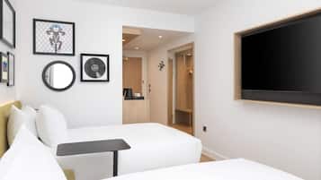 A modern hotel room with a bed, a small table, a TV, and a wardrobe.