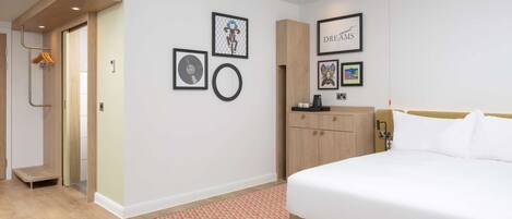 Ein modernes Hotelzimmer mit einem großen Bett, einem Holzschrank, einem kleinen Schreibtisch und einer Wand mit gerahmten Bildern.