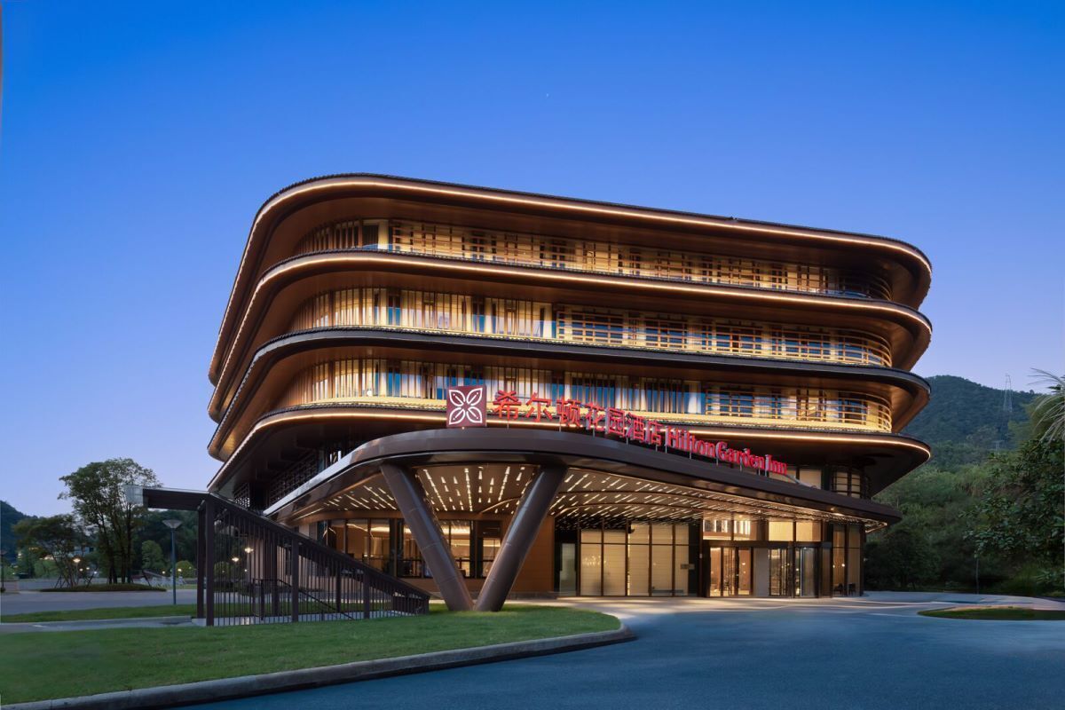 A multi-story hotel with a modern design, featuring a prominent entrance and a logo on the facade.